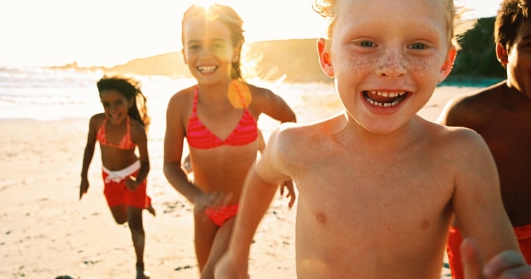 Happy, healthy children running on the beach in the sunshine, combating childhood obesity. 