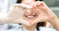 A patient and orthodontic team member making a heart shape with their hands together